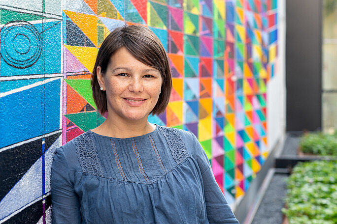 A young woman standing in front of a colourful wall: Julijana Gjorgijeva is an expert in Neurotechnology. 
