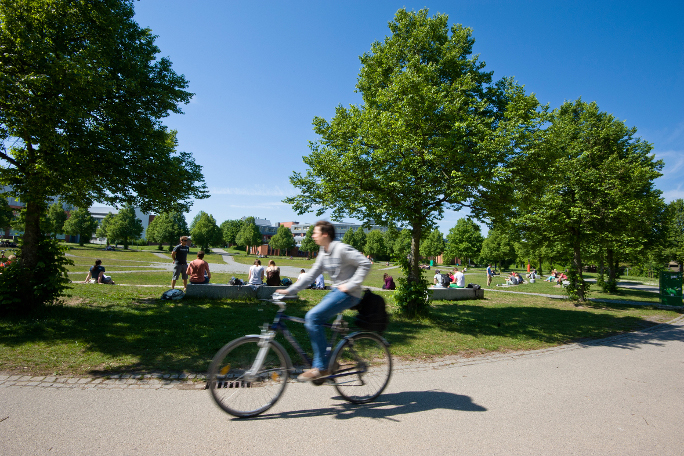 Student riding his bike through a park in Bayreuth.