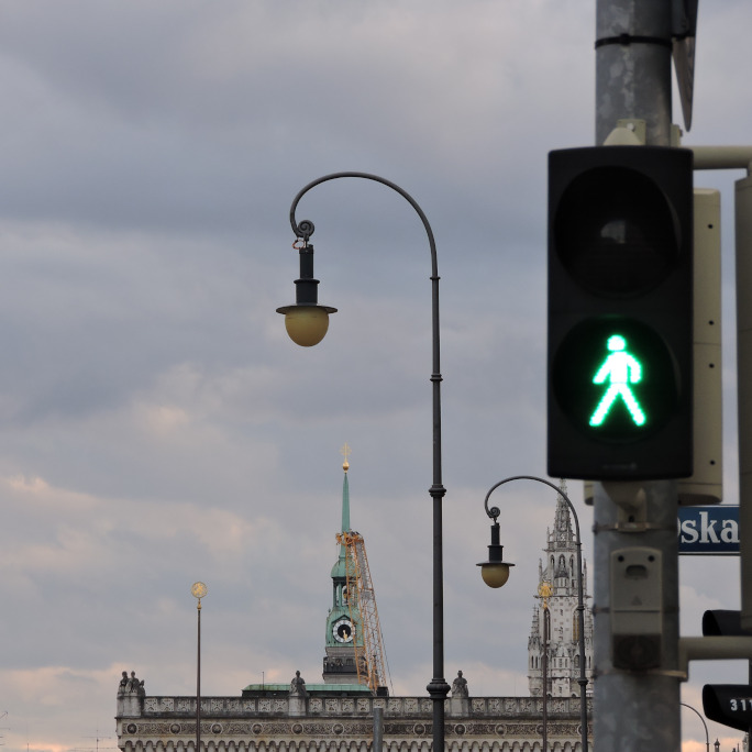 Green traffic light with skyline of Munich in the background.