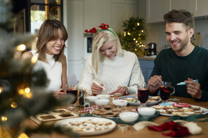 Three young people sitting at a table eating, with Christmas decoration around them