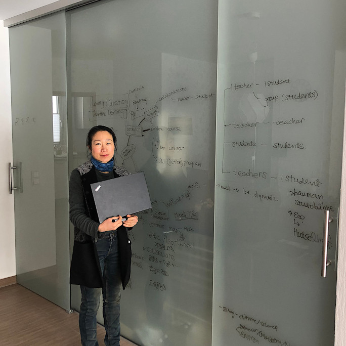 Researcher with her laptop standing in front of a sliding glass door with notes on it