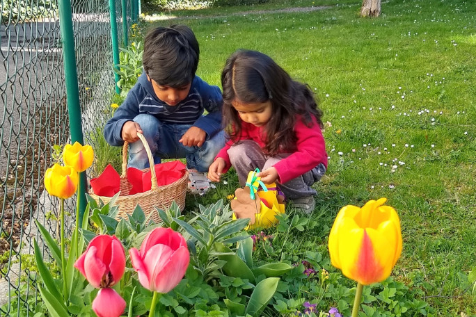 two children find easter eggs in the grass