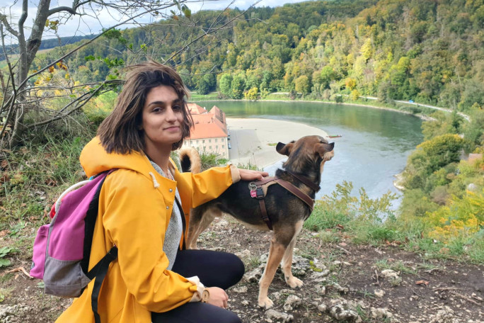 PhD student Mathilde with her dog looking at the Danube river