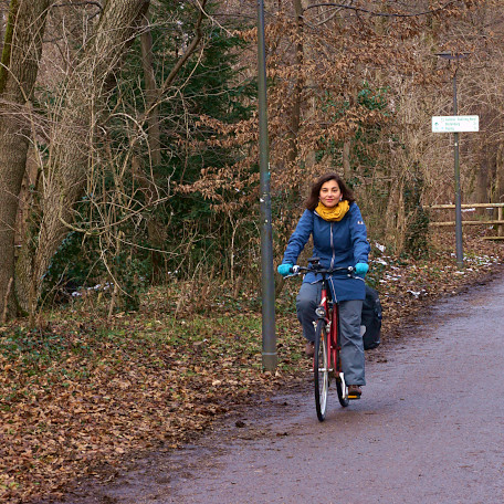 A woman cycling through a park in winter.