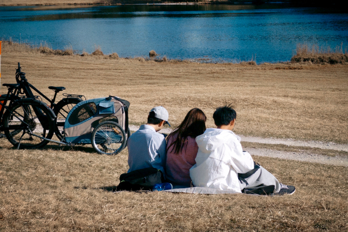 Jingkang Zhao sitting on the bank of a lake with two friends, next to some bikes