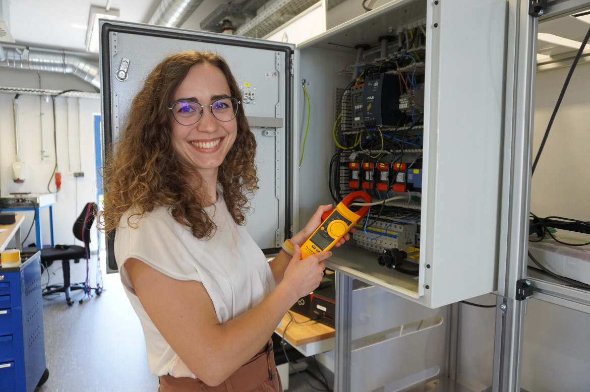 a researcher stands in front of a control cabinet for energy.