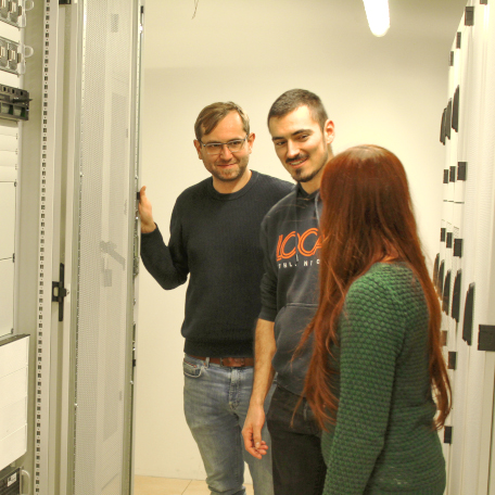 Three doctoral candidates standing in the server cabinet. 