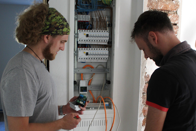 Two men in working on a electrical control box.