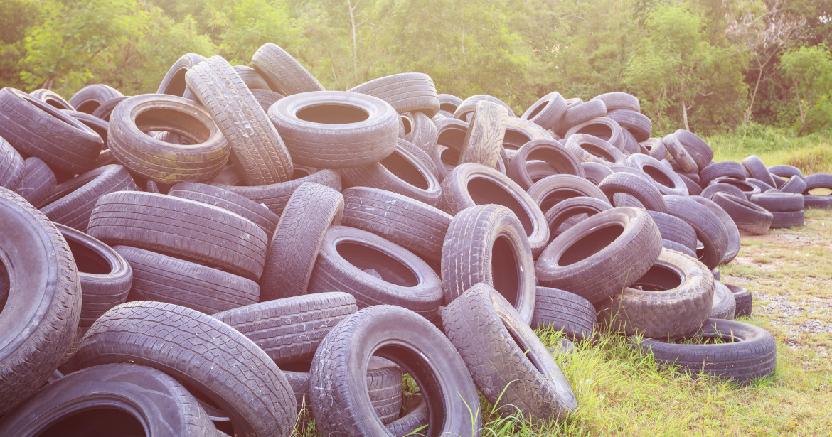 A pile of old tires lying in grass.