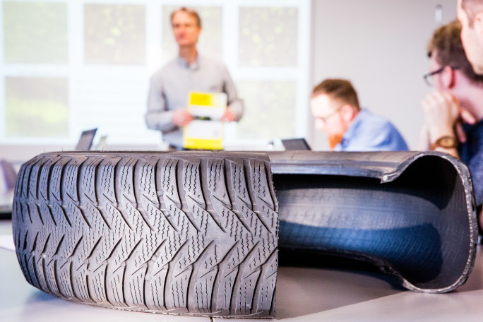 A cut tire placed on a table with students in the background.