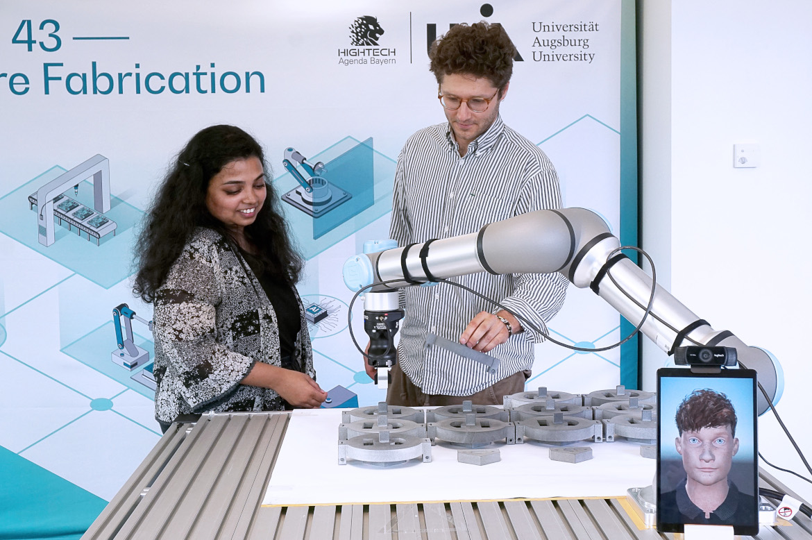Two doctoral candidates are working with a cobot .