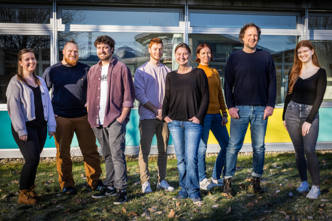 The RNA Biochemistry research group focuses on regulatory RNAs. It consists of Prof. Claus Kuhn and his seven young researchers.. They're standing outside in front of a building.