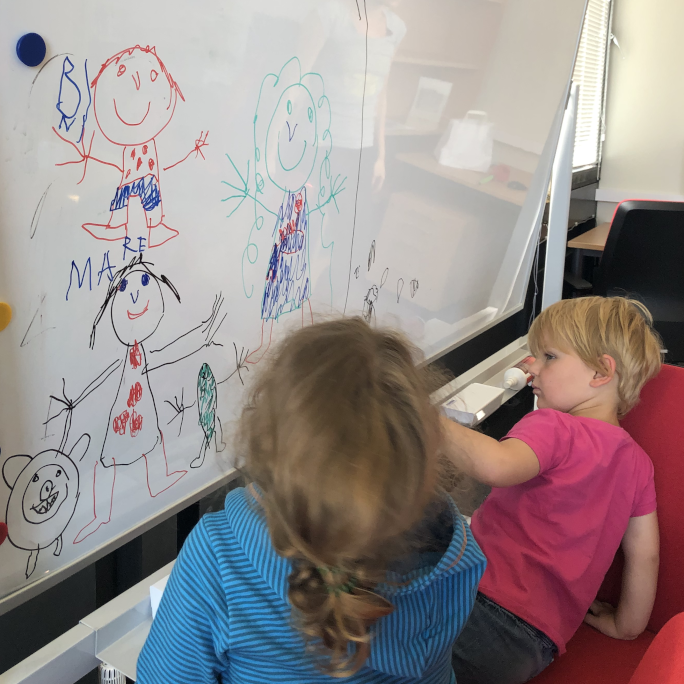 Two children painting on a white board.