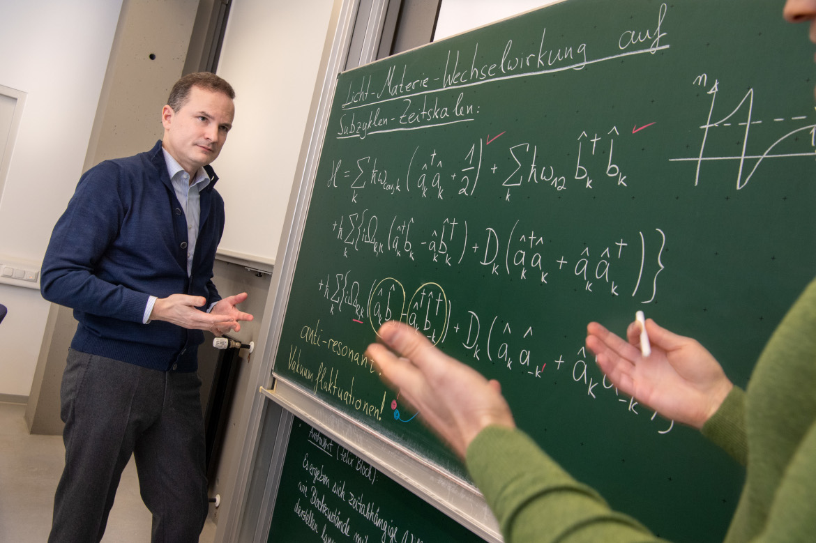 Prof. Huber in front of a board with mathematical formulas written on it