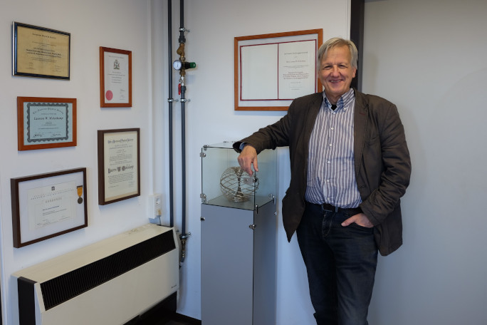 Prof. Molenkamp standing in front of a wall with awards. 