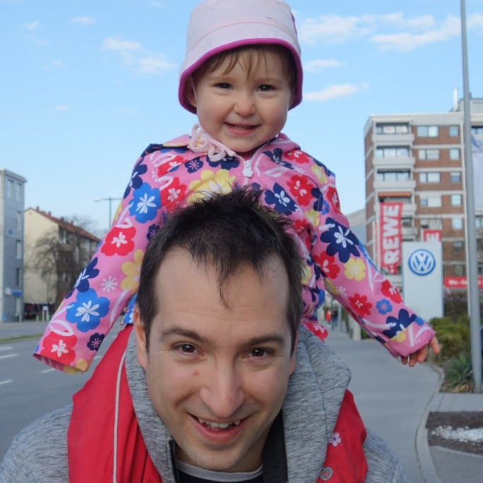 a man carrying a little girl on his shoulders