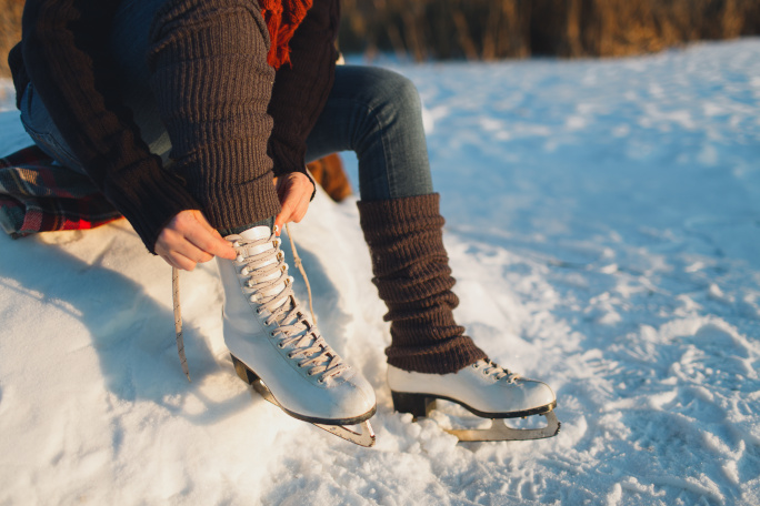 Person lacing their skate shoes in the snow