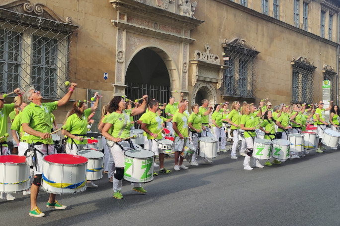 A group of people in neon green t-shirts playing the drums for the Samba festival in front of the Ehrenburg Palace