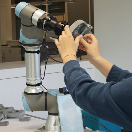 Two human hands working together with a cobot.