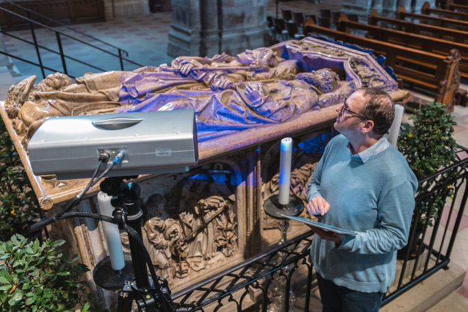 A scientics stands in a church next to a king's grave.