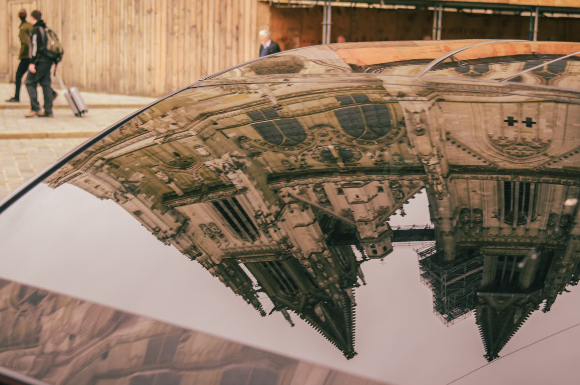 The towers of Regensburg's Cathedral mirror in the front shield of a car.