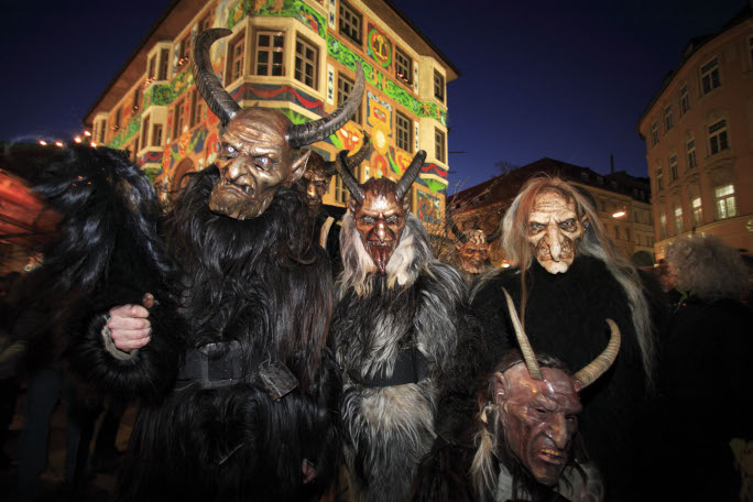 People with artistic masks dressed as Krampus in the streets in the night