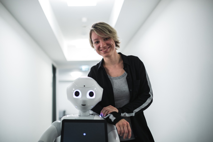 a woman standing next to a robot