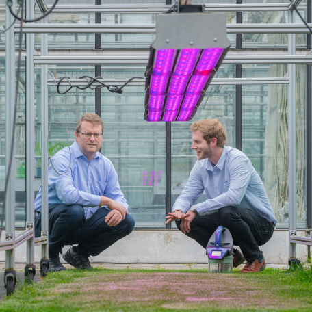 Prof. Heinz Bernhardt and a colleague, experts in precision agriculture, are inspecting grass and soil in a greenhouse.